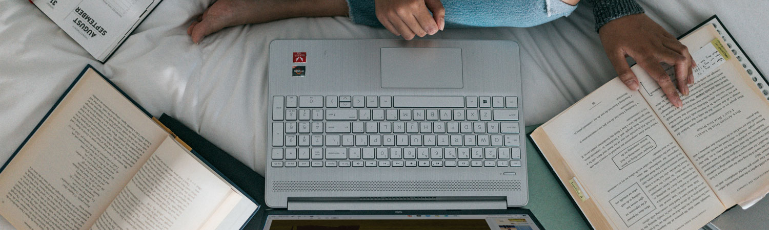 student working on laptop on their bed